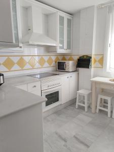 桑卢卡尔-德巴拉梅达Apartamento Nao Victoria的白色的厨房配有白色的橱柜和微波炉