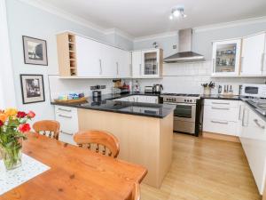 纽林Trevorrow House的厨房配有白色橱柜和木桌