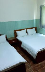 Giồng Tú ÐiềnQue Huong Coconut Hotel的配有白色床单的客房内的两张床