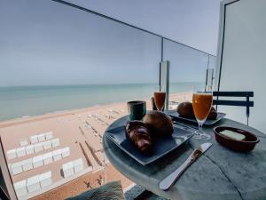 德哈恩Genieten van de Vlaamse kust met prachtig zeezicht的一张桌子,上面有一盘食物和饮料在沙滩上