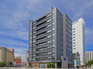 福冈Comfort Inn Fukuoka Tenjin的城市里高大的灰色建筑