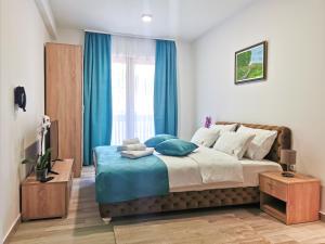 兹拉蒂博尔Hotel Agape的一间卧室配有一张带蓝色窗帘的大床