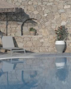 奥诺斯Mykonos Essence Adults Only的石墙旁带椅子的游泳池