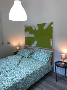 CasalzuignoAPPARTAMENTO TURISTICO - VIA MONTENUDO的一间卧室配有一张带绿色床头板的床和两盏灯。