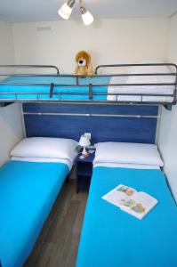 巴多利诺Happy Camp Mobile Homes in Camping Cisano San Vito的配有两张单人床的客房配有蓝色的床