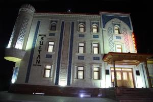 撒马尔罕苏丹精品酒店的一座白色的大建筑,晚上有灯