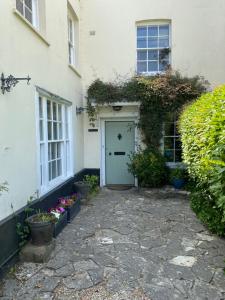 Milborne Saint AndrewHeathcote House的白色的房子,有蓝色的门和一些植物