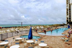 德斯坦Beachfront, Oceanview, Pelican Beach Resort, 19th Floor的海滩上的游泳池,配有桌椅