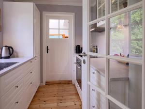 吉利勒杰6 person holiday home in Gilleleje的一间厨房,配有白色橱柜和铺有木地板的走廊