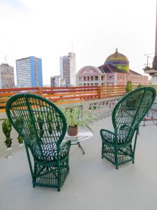 马瑙斯Hotel Casa Dos Frades的屋顶上设有两张绿色椅子和一张桌子
