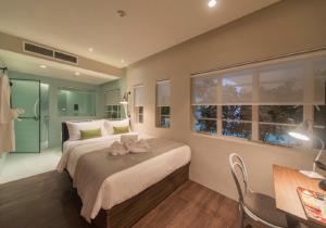 新加坡The Great Madras by Hotel Calmo的一间卧室配有一张大床、一张桌子和一个窗户。