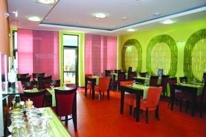 塞内奇贾尼大都会酒店的餐厅设有桌椅和粉色及绿色的墙壁