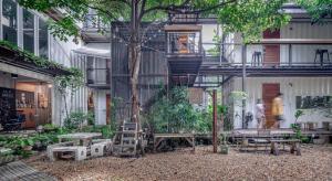 曼谷The Yard Bangkok Hostel的一座有树的建筑,有梯子和长凳