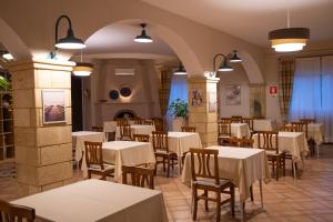 托雷奥沃科斯塔迪奥罗酒店的餐厅设有白色的桌子和木椅