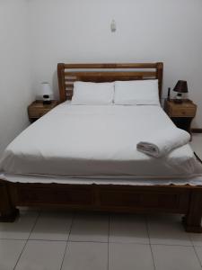 博瓦隆E&E自助旅馆的一张带白色床单和枕头的床