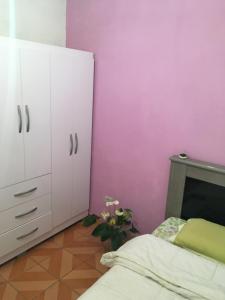 奥萨斯库Quarto INDIVIDUAL Casa Super Aconchegante WIFI 350 MEGA的卧室设有粉红色的墙壁、一张床和一个梳妆台