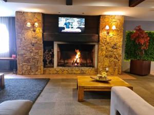 格拉玛多Alpenhaus Gramado Flat Temporada的客厅设有石制壁炉和电视