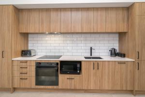 但尼丁Inner City Executive Living on Stuart Street的厨房配有木制橱柜、水槽和炉灶。