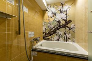 东京Hotel Karuta Akasaka的带浴缸的浴室,墙上有绘画作品