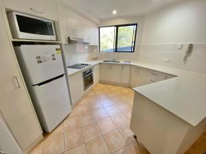 麦夸里港海滩度假酒店的厨房配有白色冰箱和水槽
