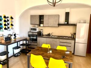 奥尔比亚Verba Mundi Guest House的厨房配有木桌和黄色椅子
