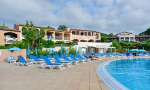 格里莫Résidence Pierre & Vacances Les Parcs de Grimaud的度假酒店的游泳池配有椅子和遮阳伞