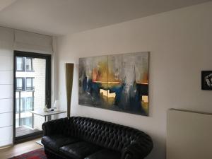 泽布吕赫Bel appartement Zeebruges的客厅配有沙发和墙上的绘画
