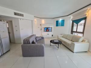 埃拉特艾姆达尔假日公寓的客厅配有两张沙发和一台电视机