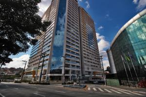 瓜鲁柳斯Flat 2211 - Guarulhos Aeroporto - Wi-fi - Estacionamento - Home Office - Shoppings的城市街道上一座高大的建筑,设有玻璃窗
