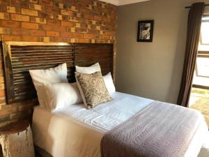 米德尔堡Rondebosch Eco Cottages的卧室内的一张床位,卧室设有砖墙