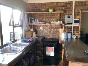米德尔堡Rondebosch Eco Cottages的厨房配有水槽和炉灶 顶部烤箱