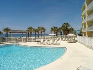 巴拿马城海滩Boardwalk Beach Hotel的一座带椅子和遮阳伞的游泳池位于一座建筑旁边