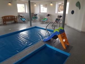 StavsøHennebjerg overnatning的客房设有带滑梯和椅子的游泳池。