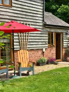 莱明斯特Archers Cottage的一把红伞,坐在椅子和房子旁边