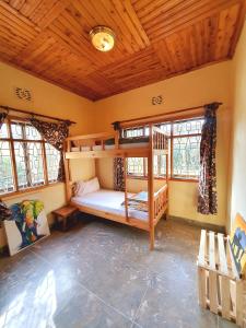 阿鲁沙Mazzola Safari House & Backpacking的一间带双层床的卧室,位于带木制天花板的房间内