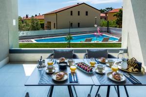 乌马格Rocca Riviera Umag Luxury Apartments的一张桌子,上面有食物,享有游泳池的景色