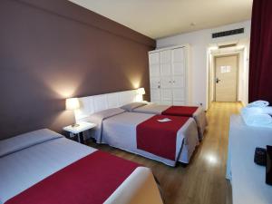 普拉托总统酒店的酒店客房带两张红色和白色的床单