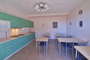 卡巴丁卡Naytilus family Hotel的厨房配有绿色橱柜和桌椅