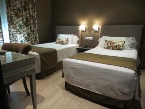 马德里Hotel Moderno Puerta del Sol的酒店客房配有两张床和一张书桌