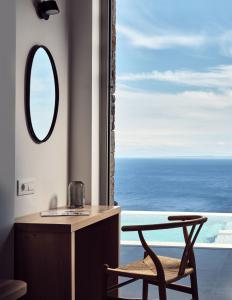 圣尼古拉奥斯Etheria Luxury Villas & Suites的浴室设有镜子和靠窗的椅子