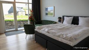 SkálavíkMølin Guesthouse的卧室配有床、椅子和窗户。