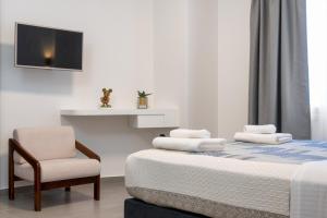 雅典Glyfada Gallery Apartment的一间卧室配有一张带椅子的床和一台电视