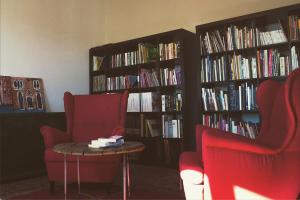 圣马力诺La casa di Montegiardino的图书馆配有两把椅子、一张桌子和书籍