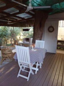 赫卢赫卢韦Lebombo Wattle Cottage - Forest 1的甲板上配有两把白色椅子和一张桌子