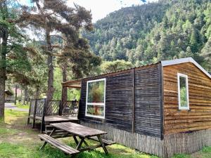 Le MartinetCamping River的小木屋设有野餐桌和长凳