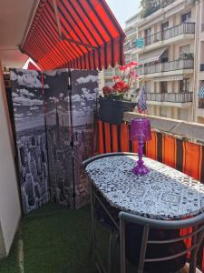 尼斯CHAMBRE CHEZ L'HABITANT - ROOM IN THE OWNER'S APARTMENT的阳台配有桌椅和遮阳伞