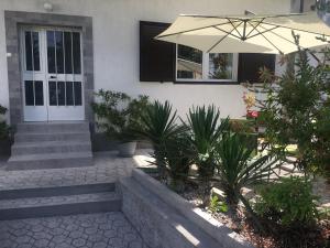 奥帕提亚Apartment Paola的一座带雨伞和一些植物的白色房子