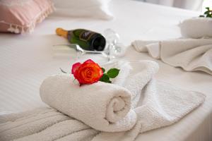 帕莱欧卡斯提撒Nausika Cottage Corfu的床上的毛巾,带玫瑰和一瓶葡萄酒