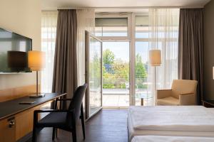 波茨坦Seminaris Hotel Potsdam Griebnitzsee的配有一张床、一张书桌和一扇窗户的酒店客房