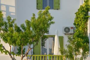 阿达玛斯Zeras Apartments的一座带绿门和遮阳伞的房子